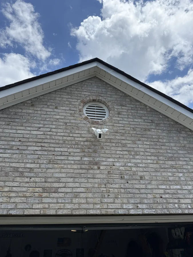 Closer view of the floodlight camera mounted on the brick gable